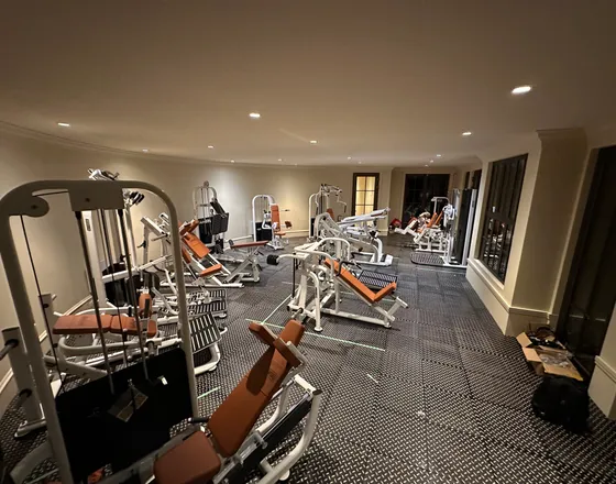 A home gym mid-move, with weight machines placed across a rubber-tiled floor