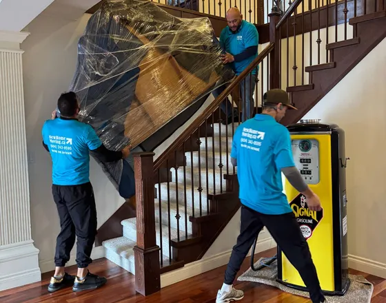Three movers carrying furniture down a stairwell