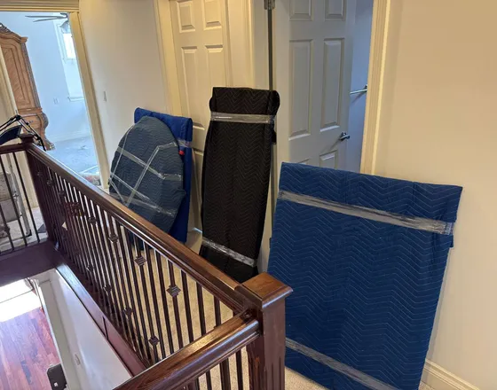 A single piece of furniture wrapped and carried through a hallway