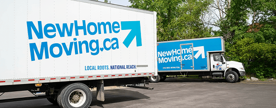 Two New Home Moving trucks parked in Surrey BC showing the company logo and slogan “Local Roots. National Reach.”